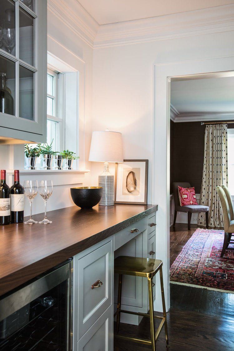 A kitchen counter with bottles of wine and glasses on it.