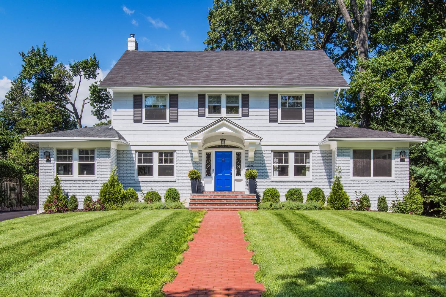 A white house with a blue door and a red walkway