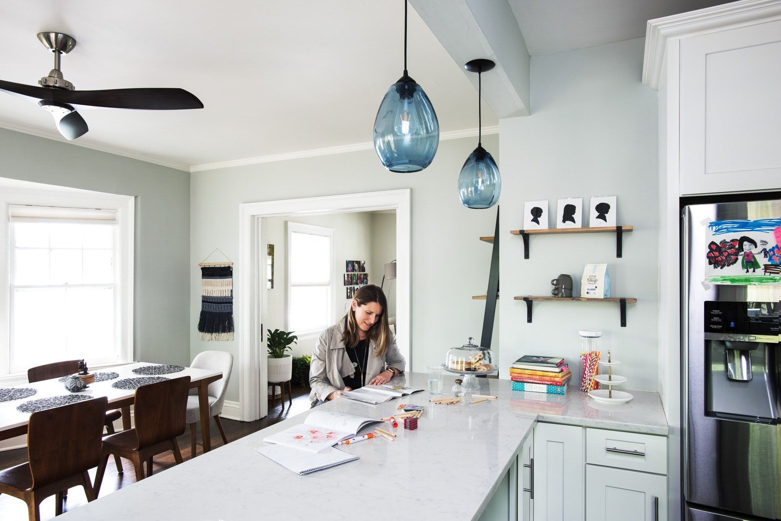 A woman is sitting at a counter in a kitchen.