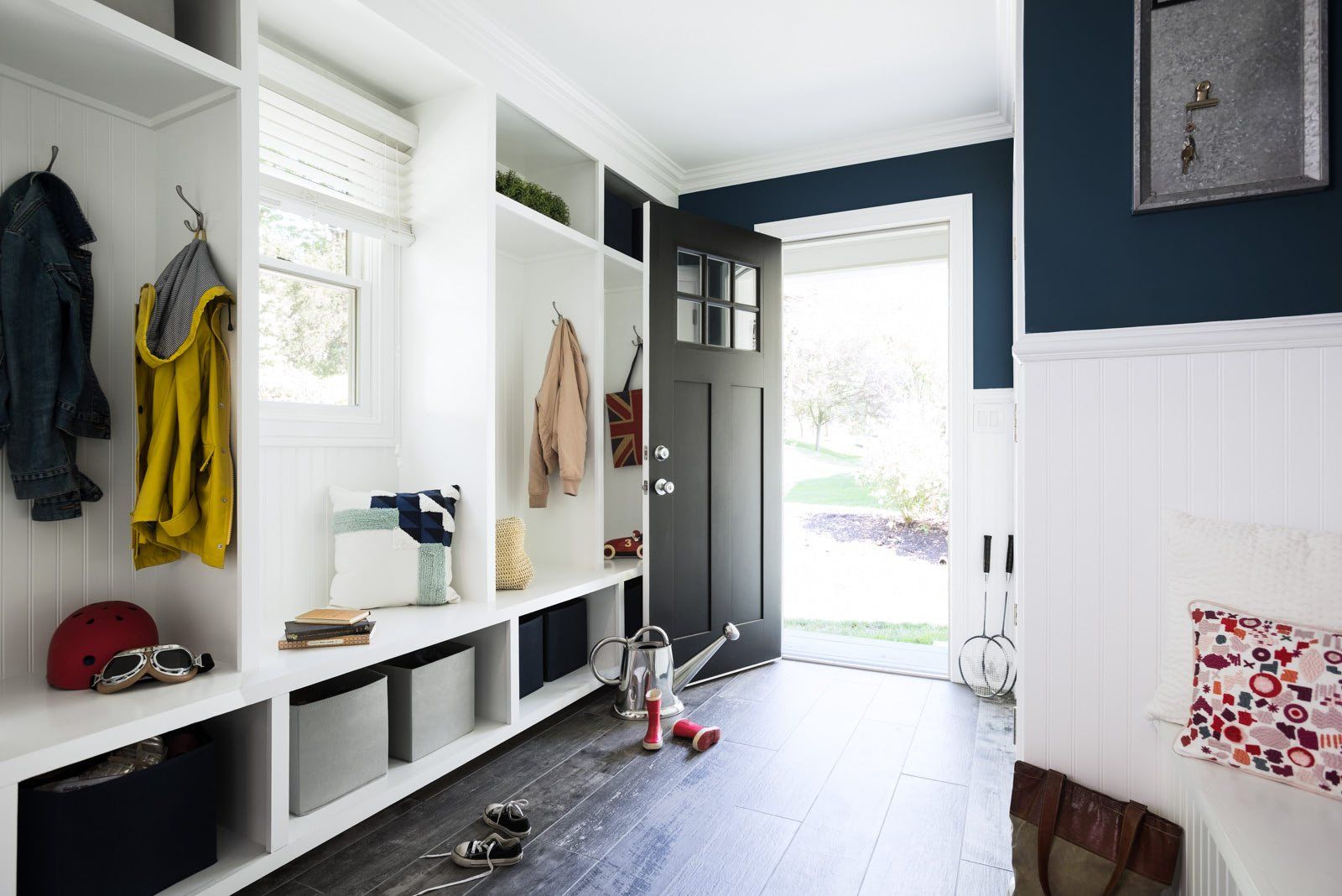 A hallway with a black door and white shelves.