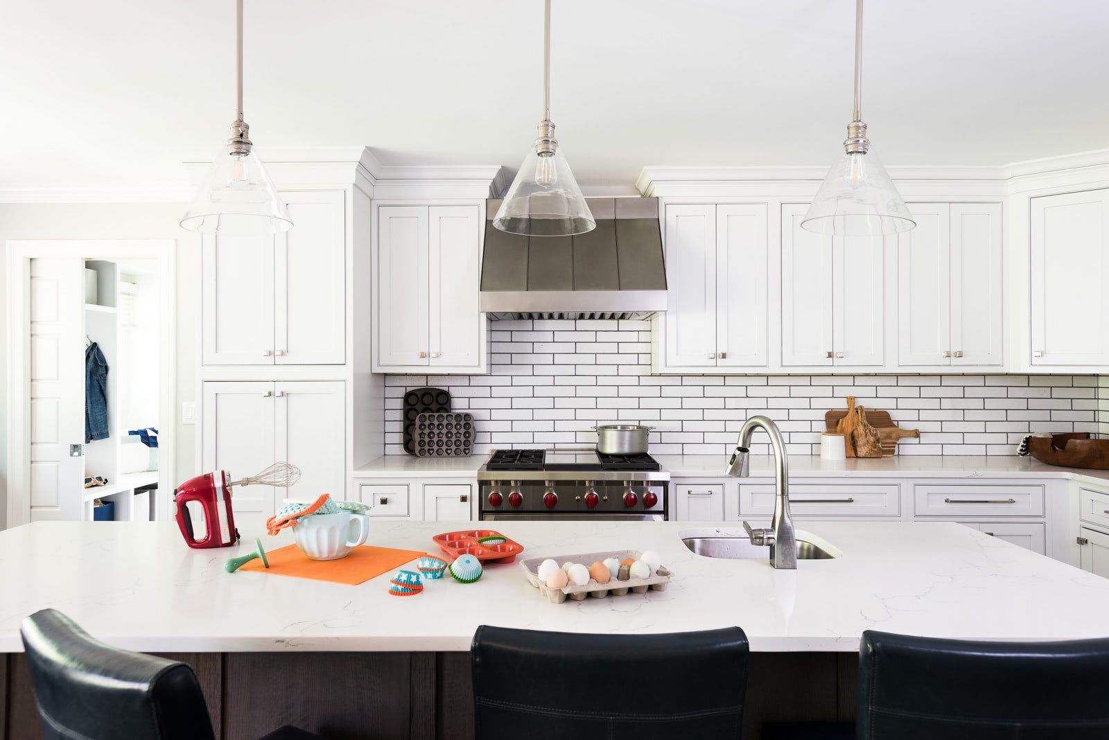 A kitchen with white cabinets , a stove , a sink , and a large island.