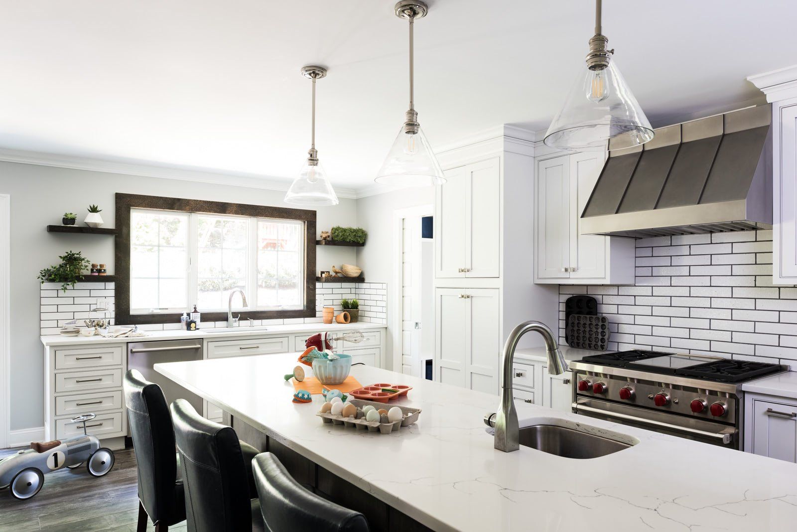 A kitchen with white cabinets , a sink , a stove , and a toy car.
