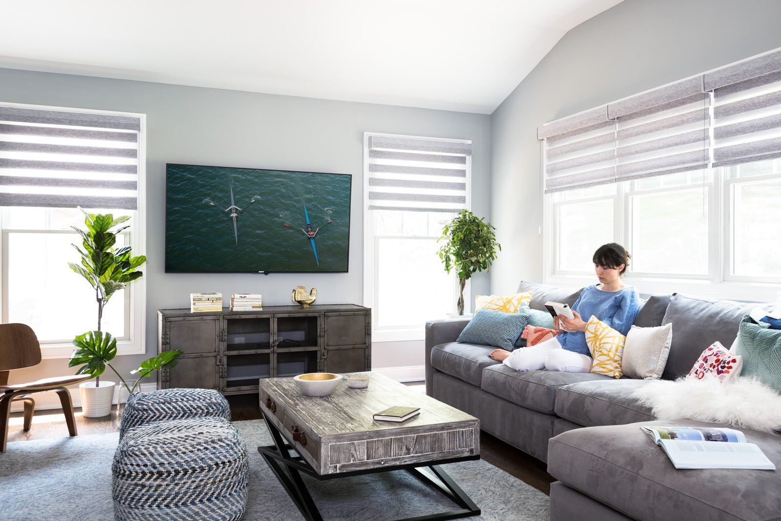 A woman is sitting on a couch in a living room looking at her phone.