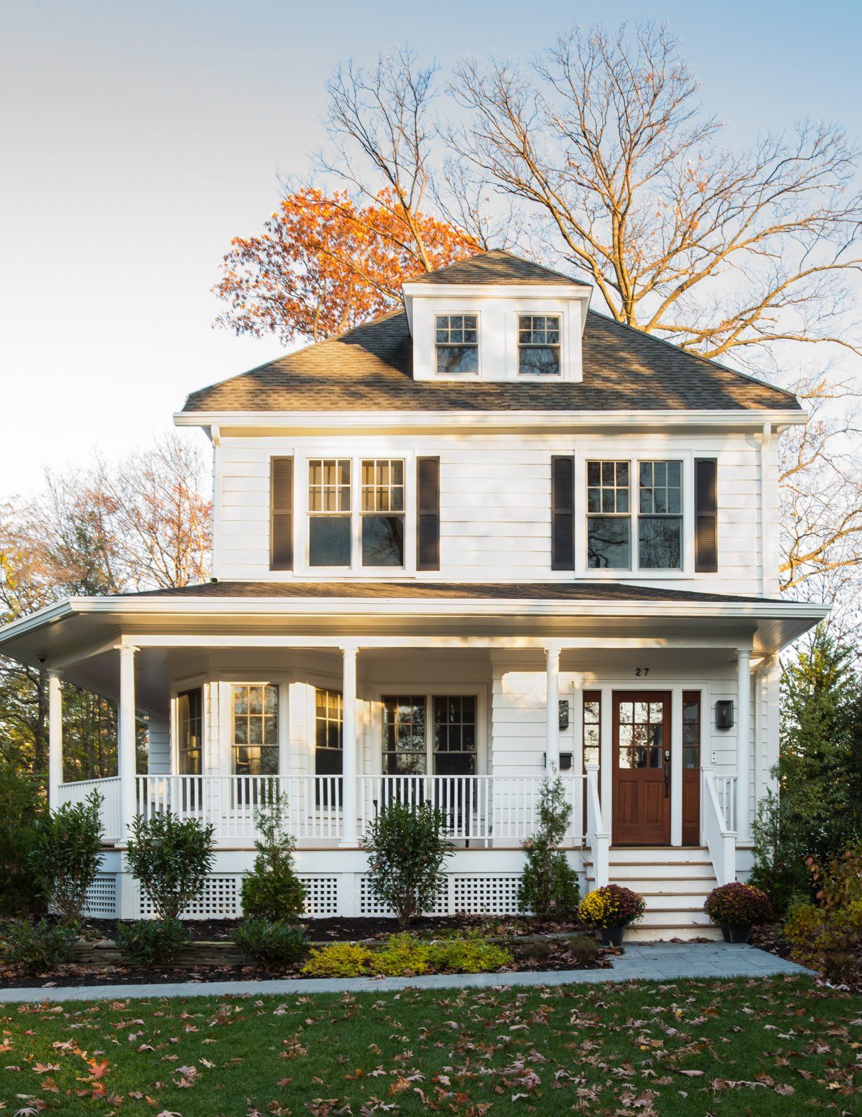A large white house with a porch and trees in the background