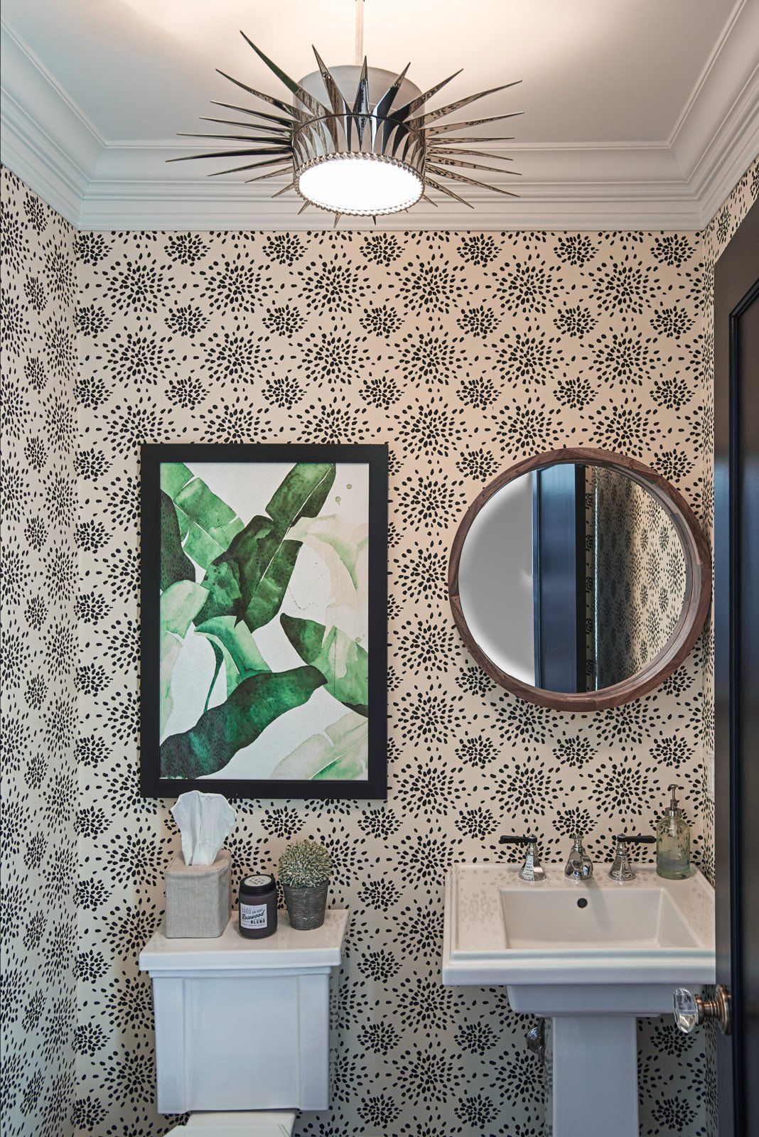 A bathroom with a toilet , sink , mirror and a picture on the wall.
