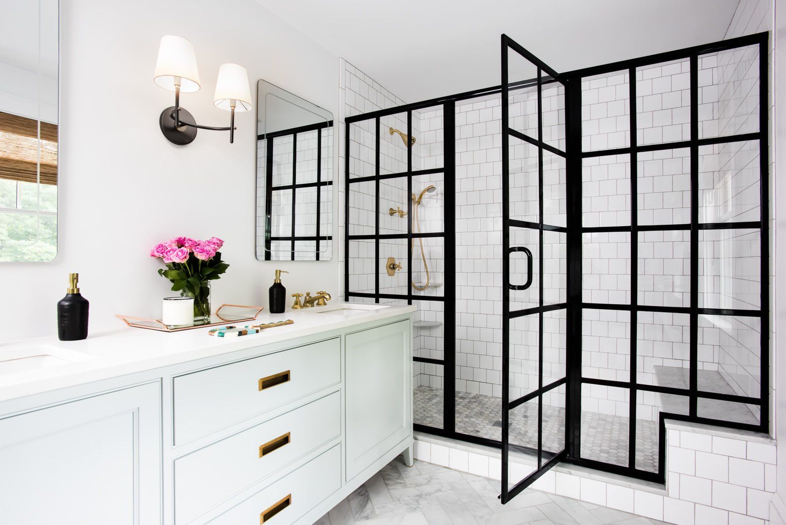 A bathroom with white cabinets , a sink , a mirror and a walk in shower.