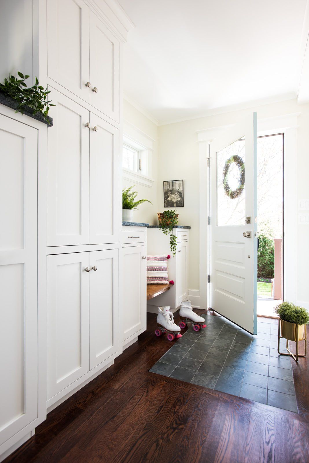 A hallway with white cabinets and roller skates on the floor.