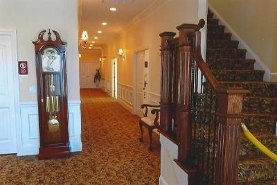 Elegant hallway with carpet, grandfather clock, and staircase with wooden banister