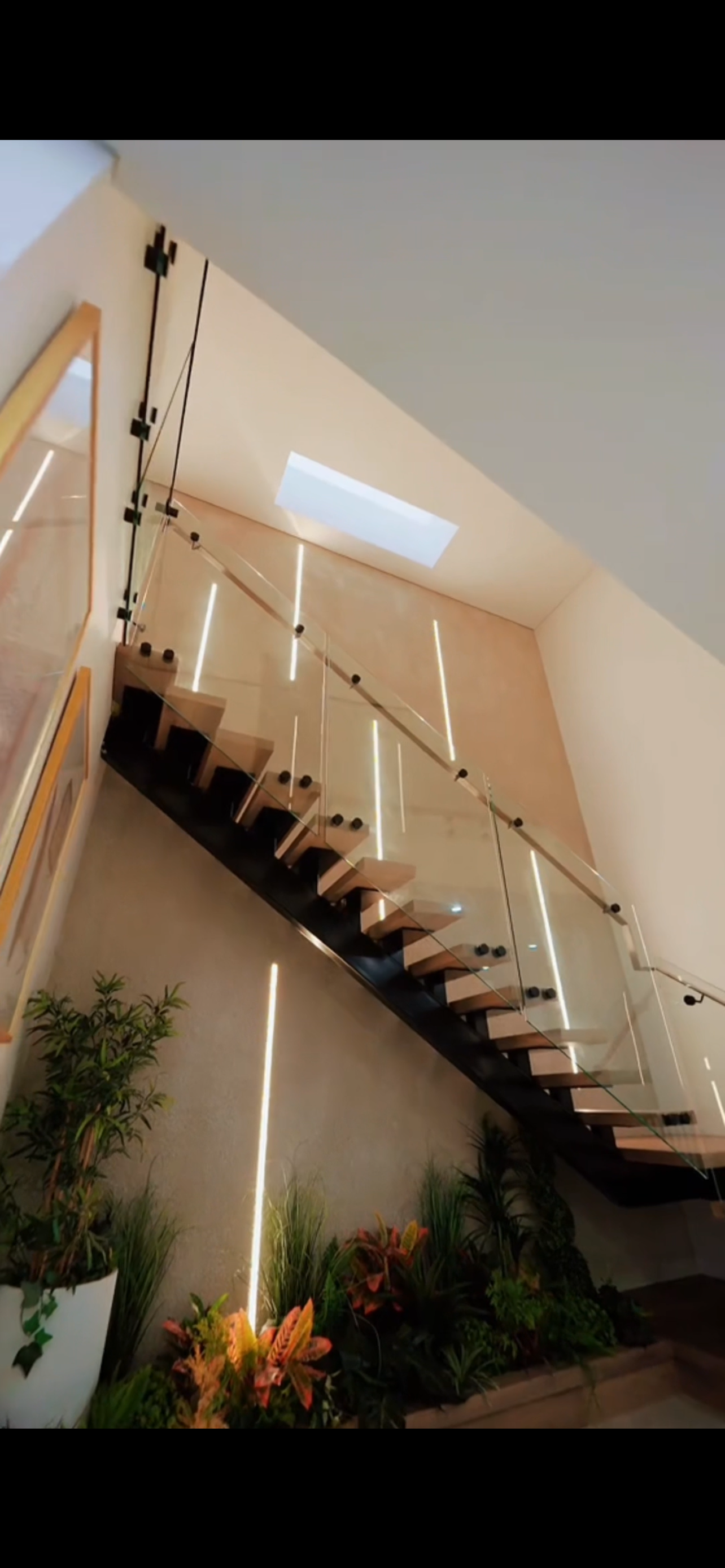 A staircase with a glass railing and a skylight.