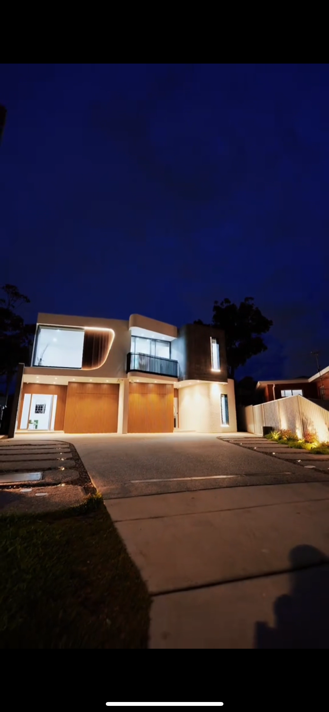A house is lit up at night with a blue sky in the background.