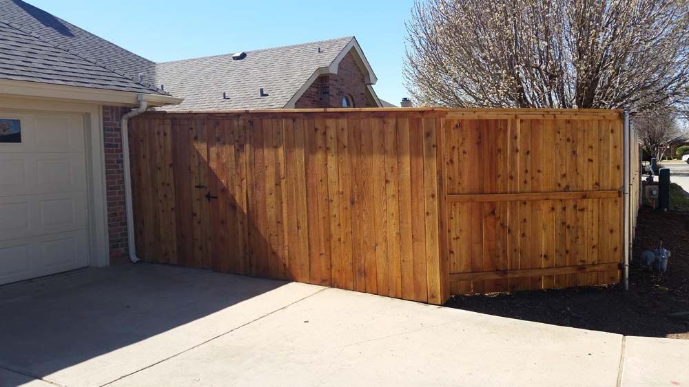 Wooden privacy fence beside a driveway and garage in a suburban home.