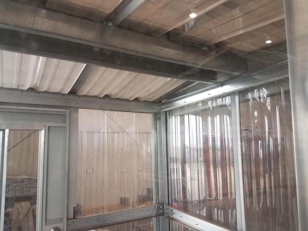 Indoor patio with corrugated metal roof, translucent wall panels, and a bench against the wall