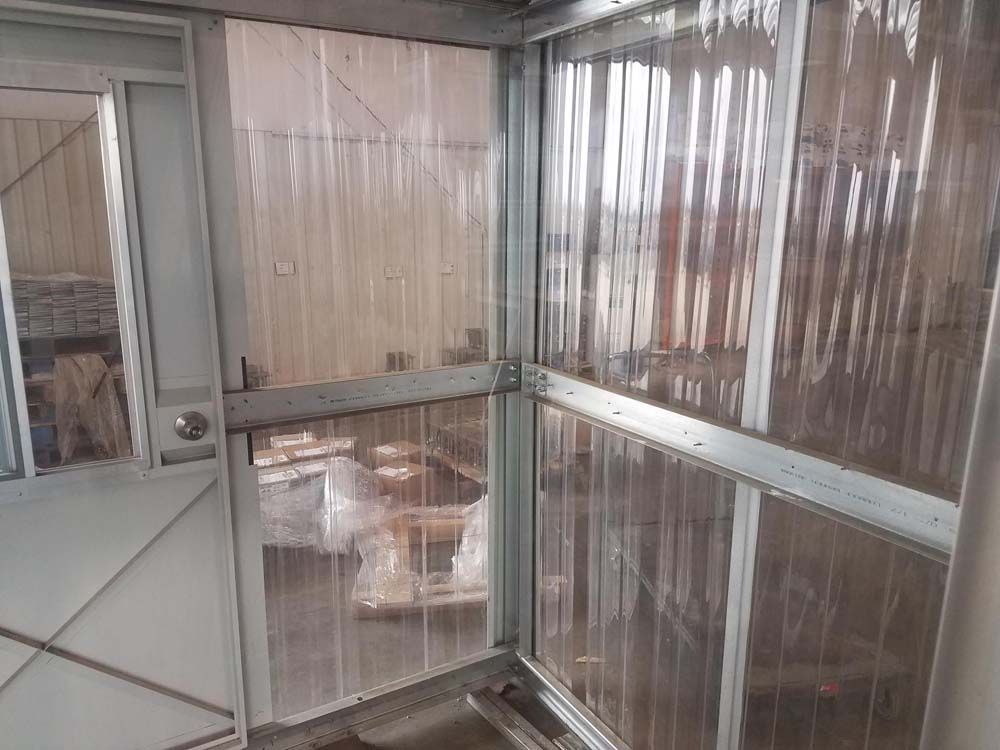 Enclosed porch with clear plastic panels, a screen door, and chairs in the background