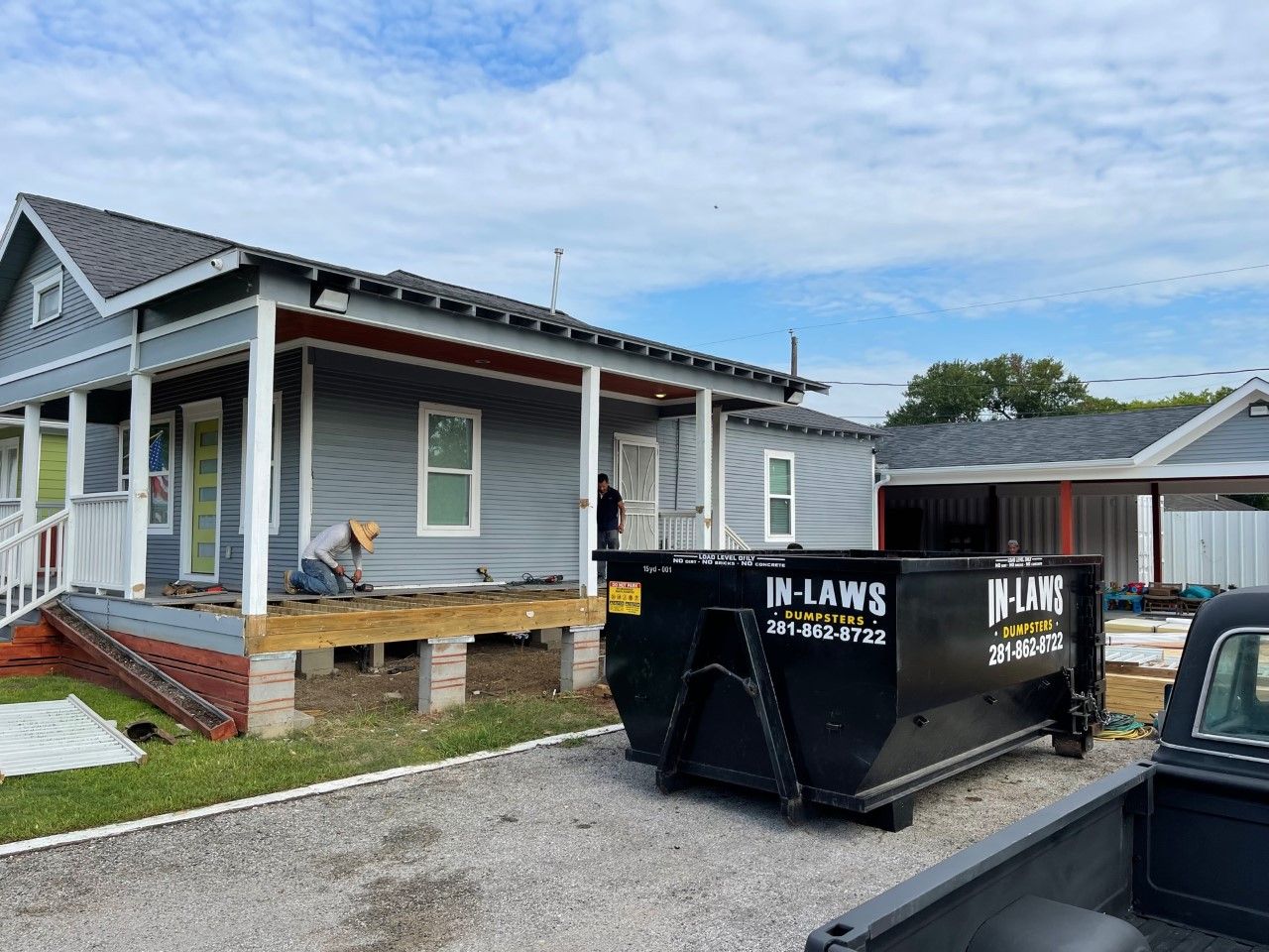 A dumpster is parked in front of a house under construction.