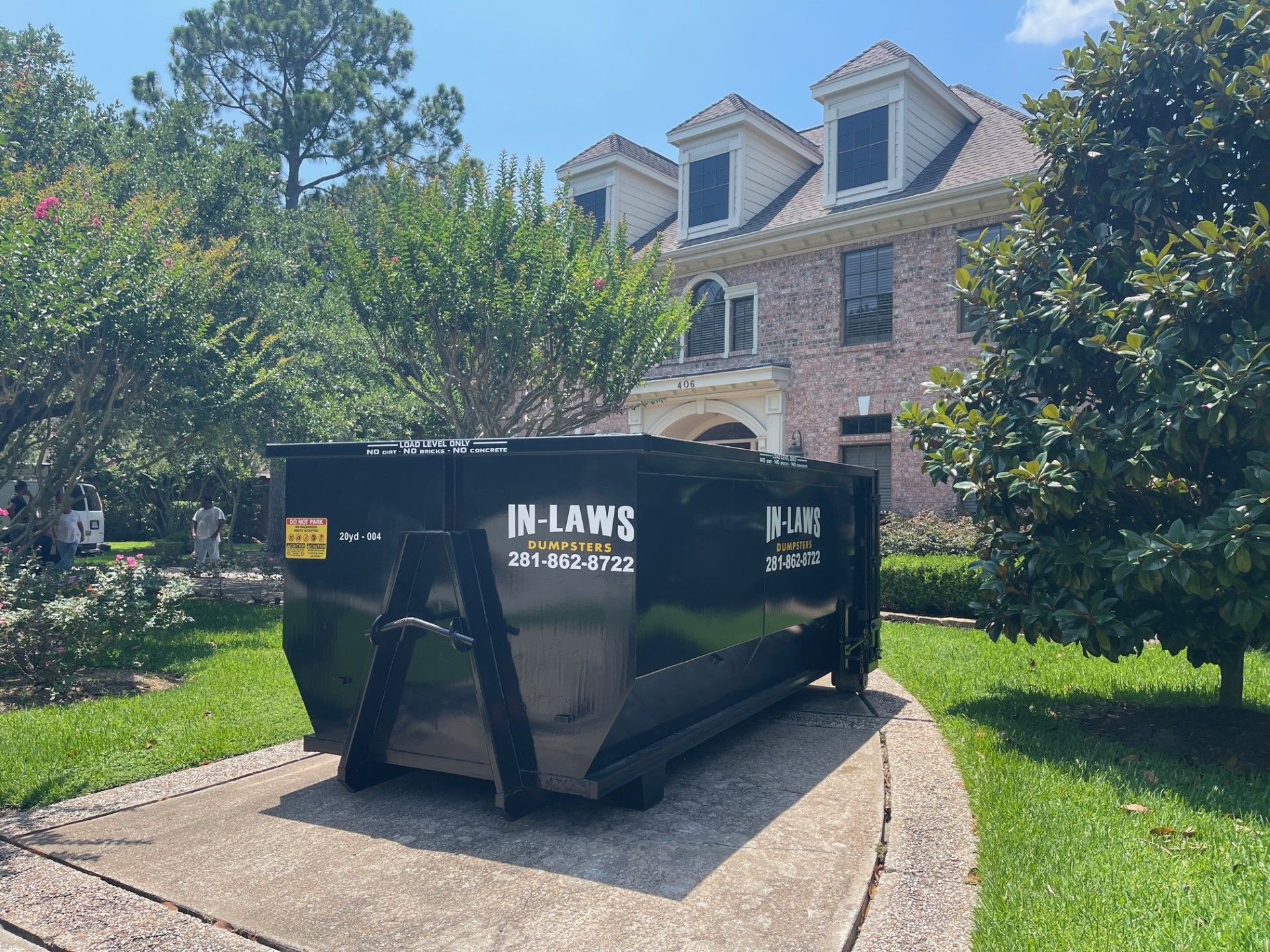 A dumpster is parked in front of a large house.