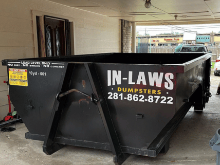 A dumpster for in-laws dumpsters is parked in front of a house.