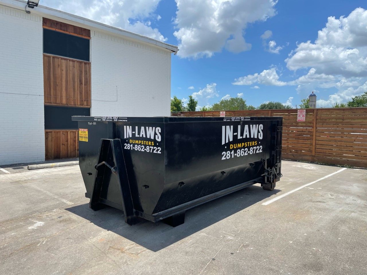 A dumpster is parked in a parking lot in front of a building.