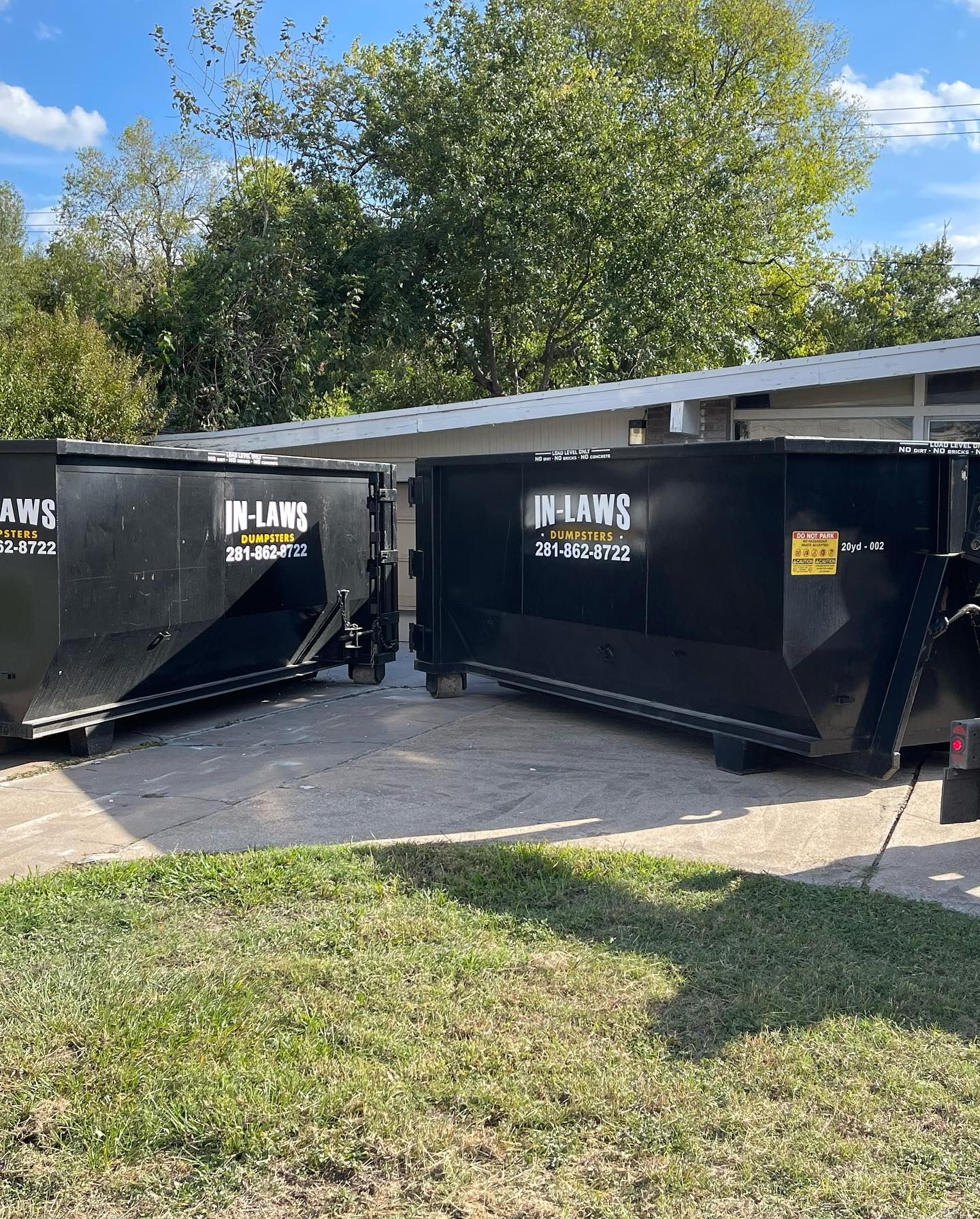 Two dumpsters are parked next to each other in a driveway.