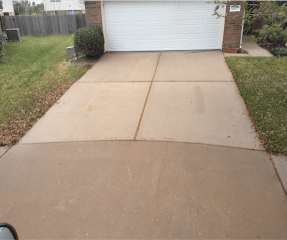 A concrete driveway leading to a garage with a white garage door.