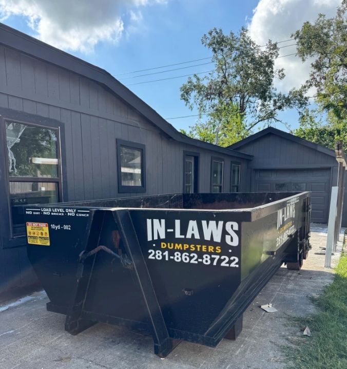 Roofing crew loading tear-off debris into a rented dumpster