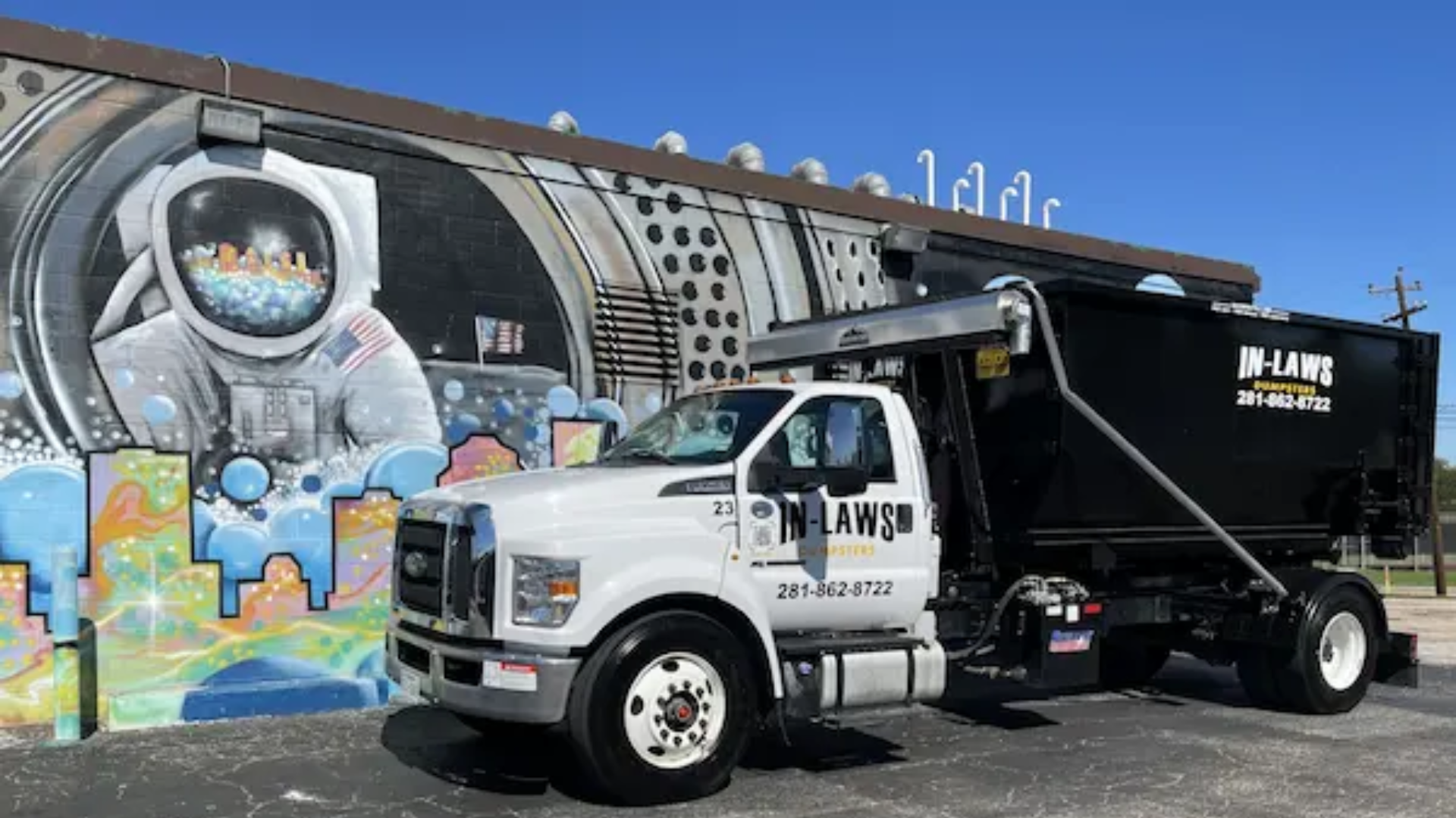 A dump truck is parked in front of a building with graffiti on it.