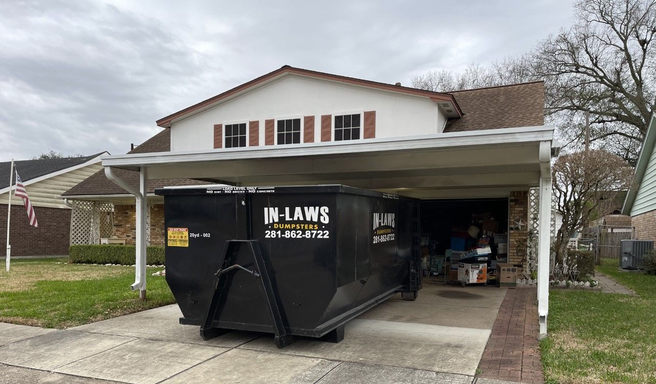 A dumpster is parked in the driveway of a house.