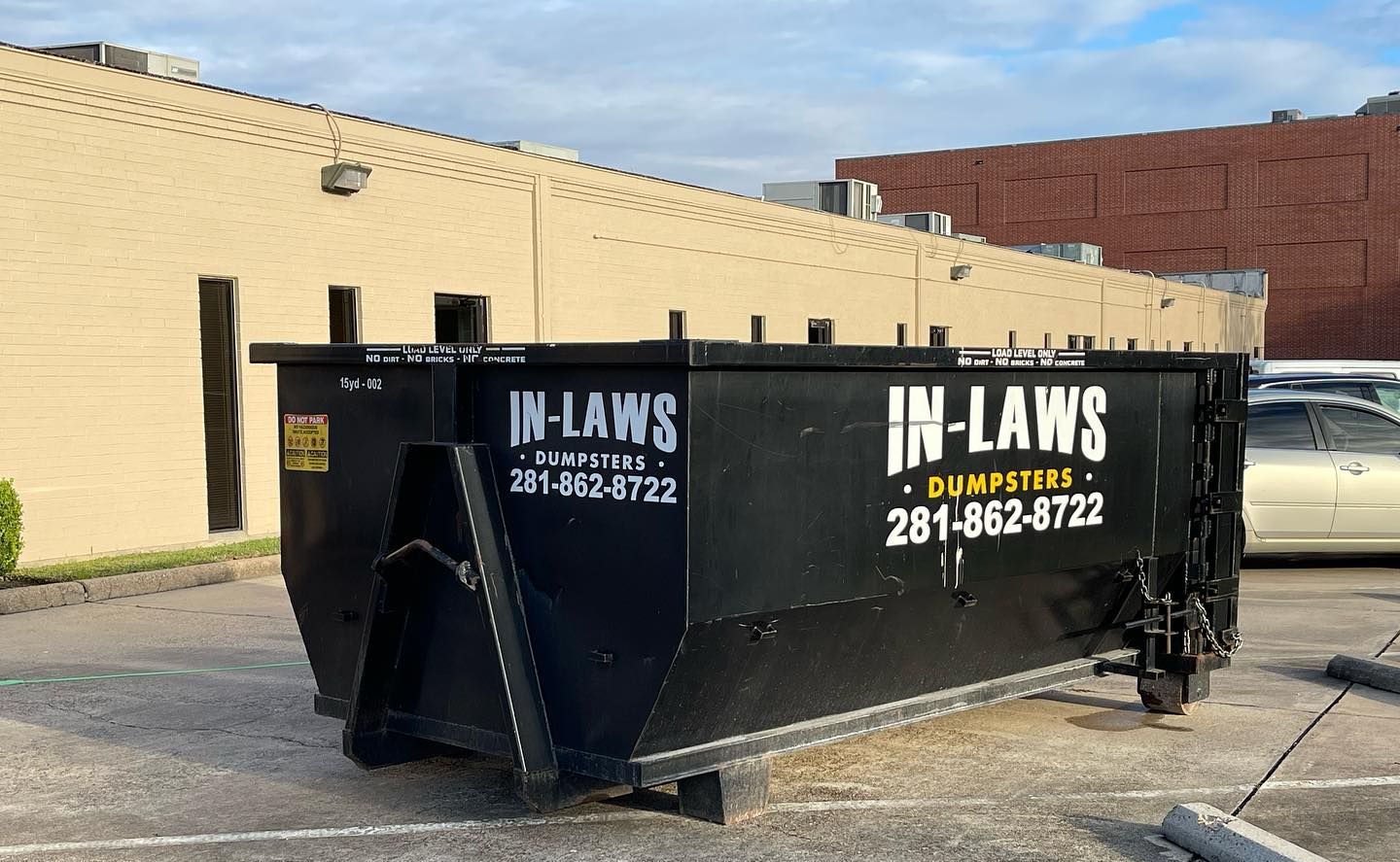 A dumpster is parked in a parking lot in front of a building.