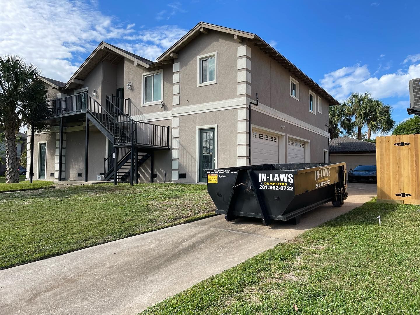 A dumpster is parked in front of a large house.