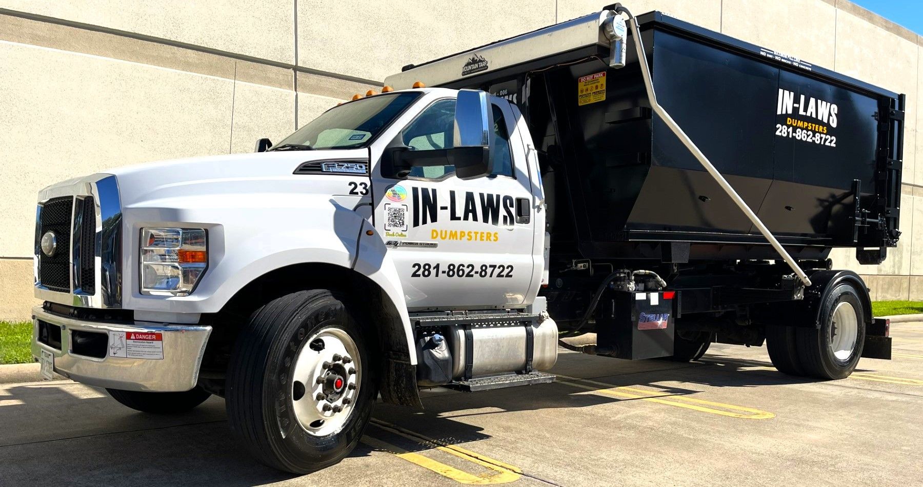 A dump truck is parked in a parking lot next to a building.