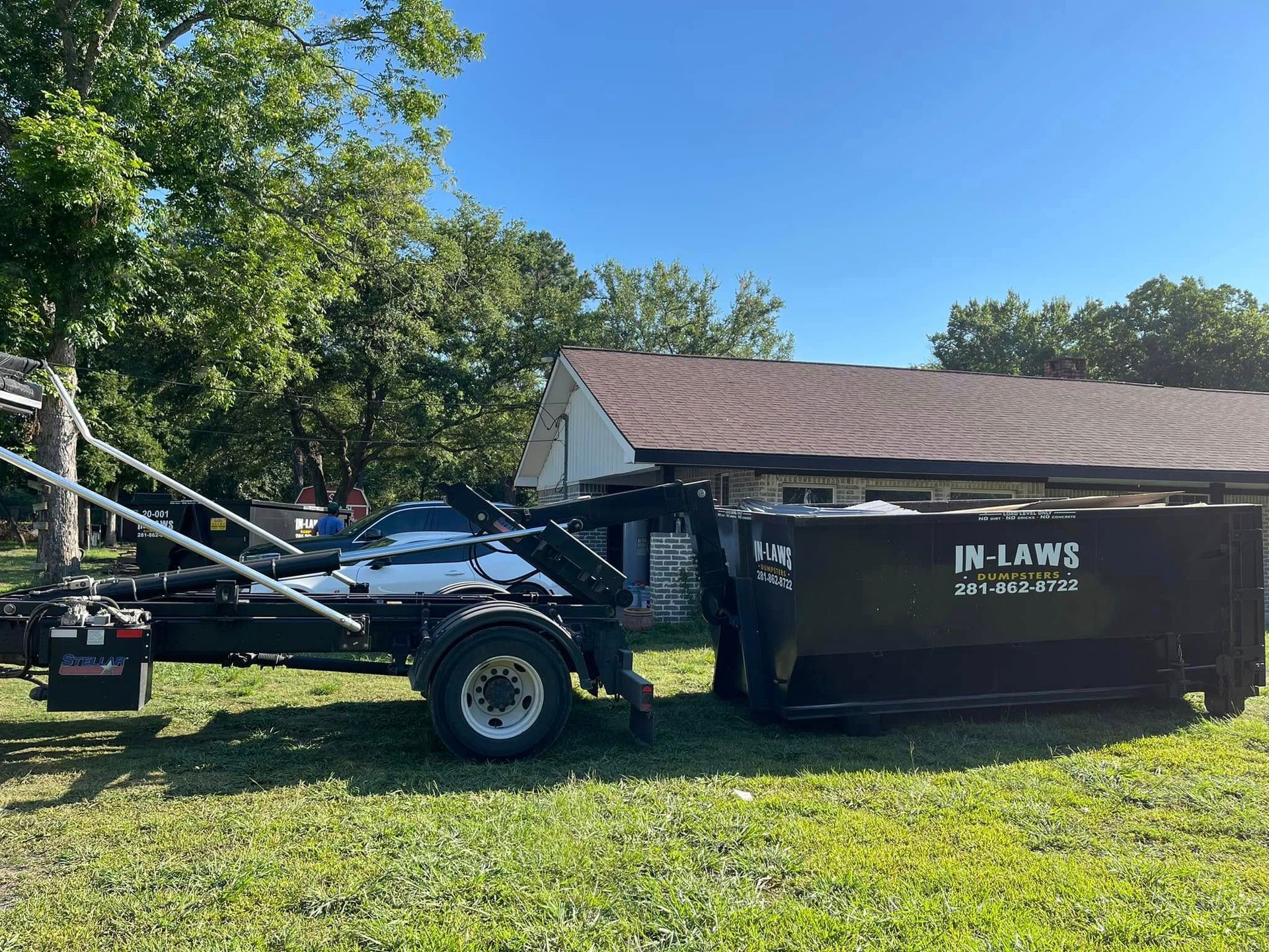 In-Laws truck delivering a roll-off dumpster to a Houston home