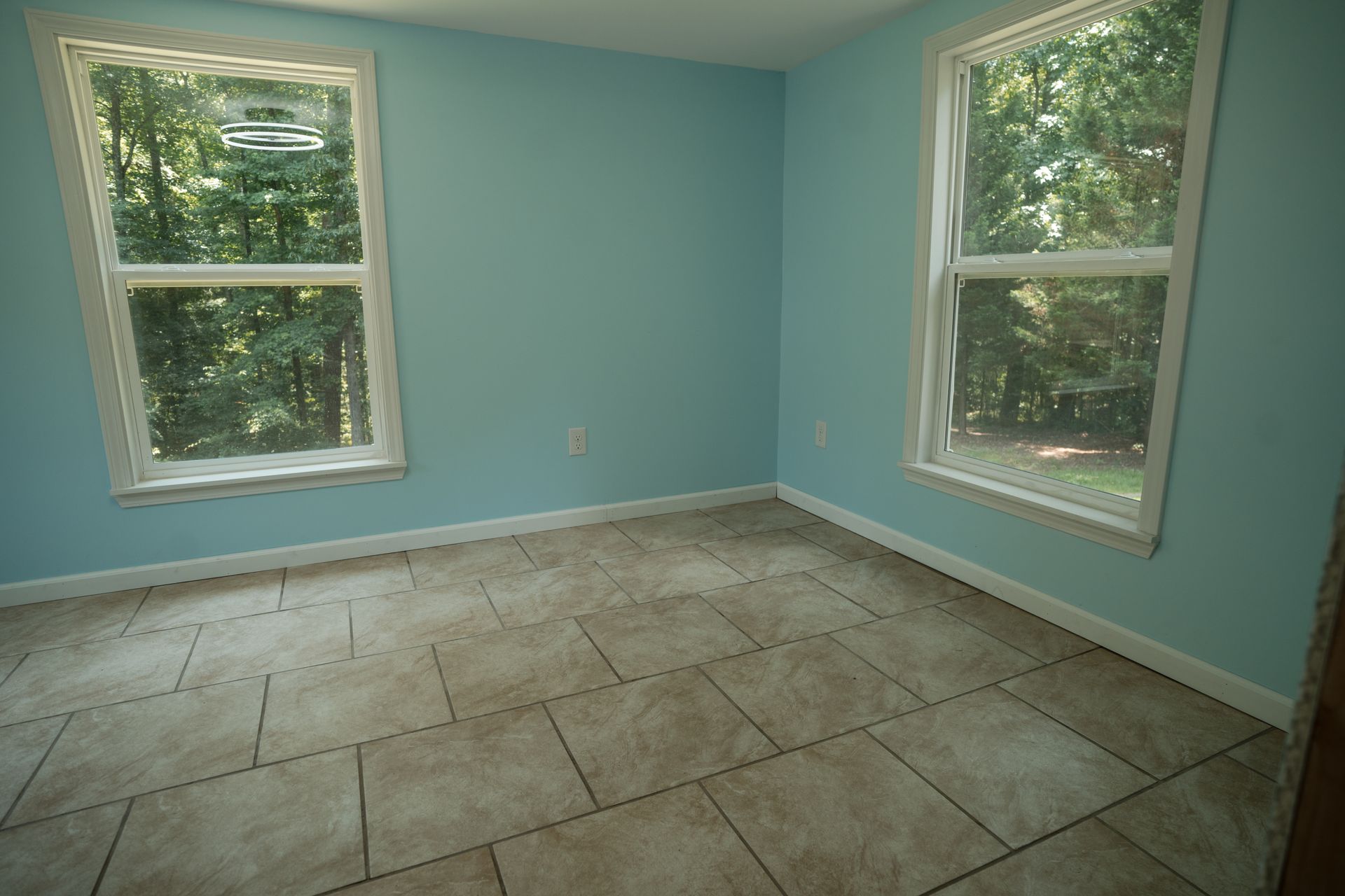 Empty blue room with large windows and tiled floor