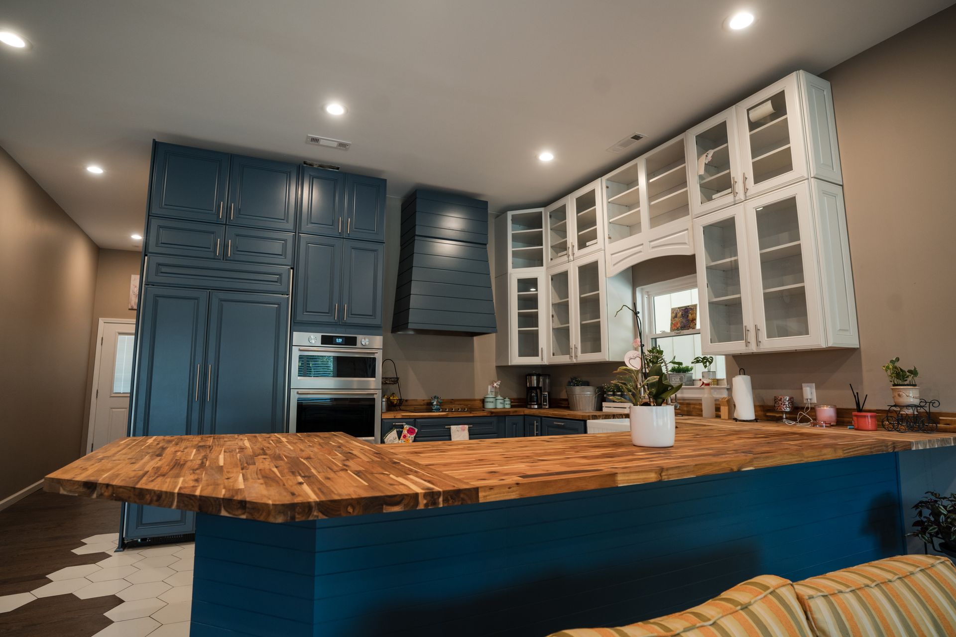 Modern kitchen with blue cabinets, white glass-front upper cabinets, and a large wooden island counter