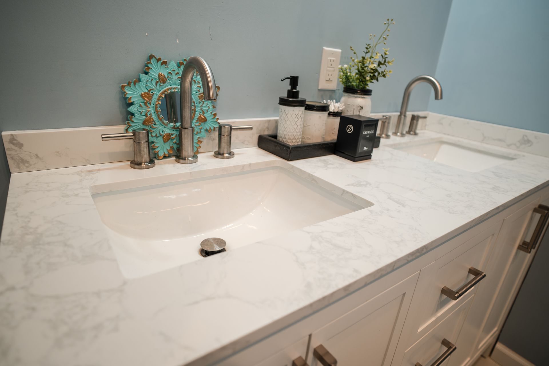 White bathroom vanity with marble countertop, sink, mirror, and toiletries on the counter