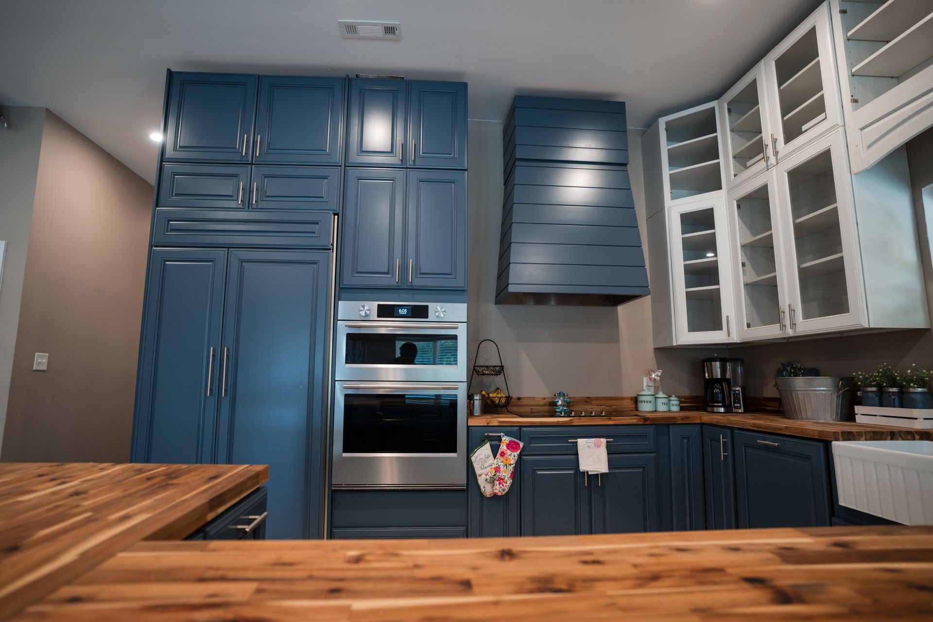 Modern kitchen with blue cabinets, stainless steel oven, and wood countertops