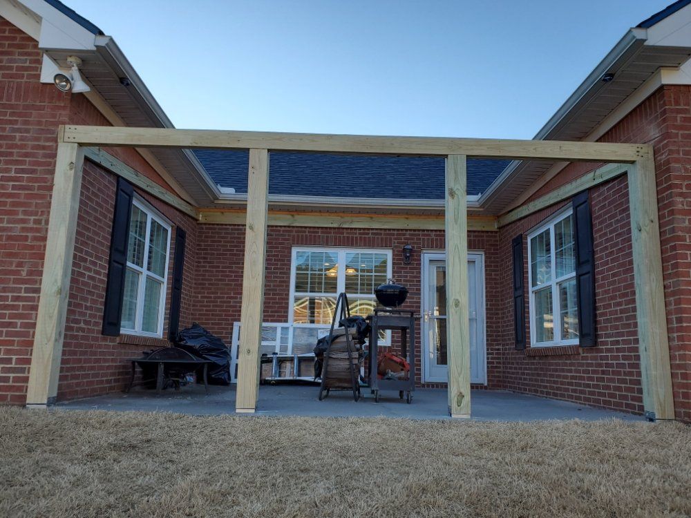 Brick patio with wooden pergola, grill, and outdoor seating between two houses