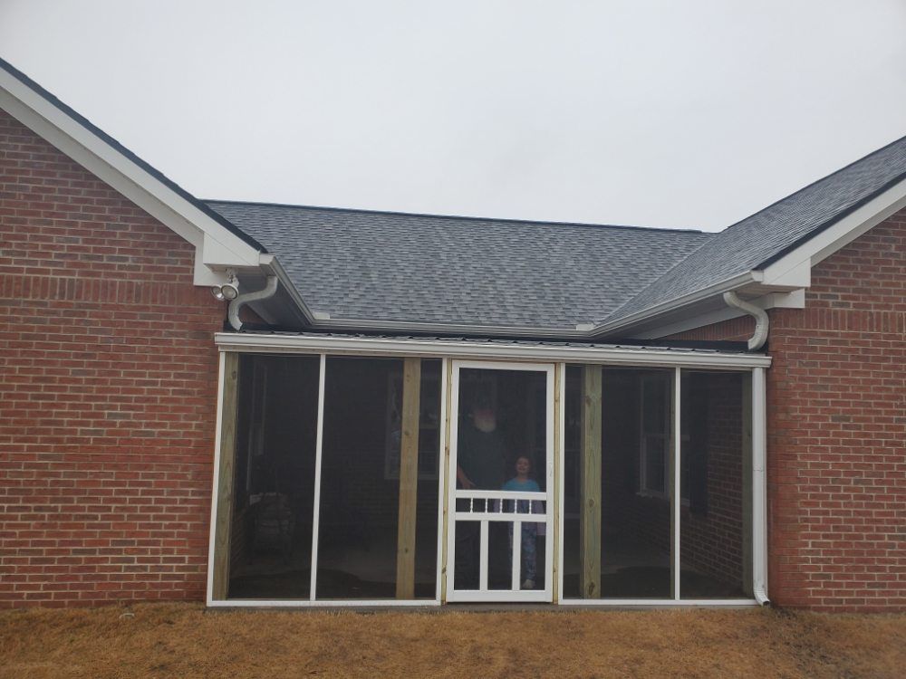 Brick house front porch with screened windows and a small white door under a gabled roof