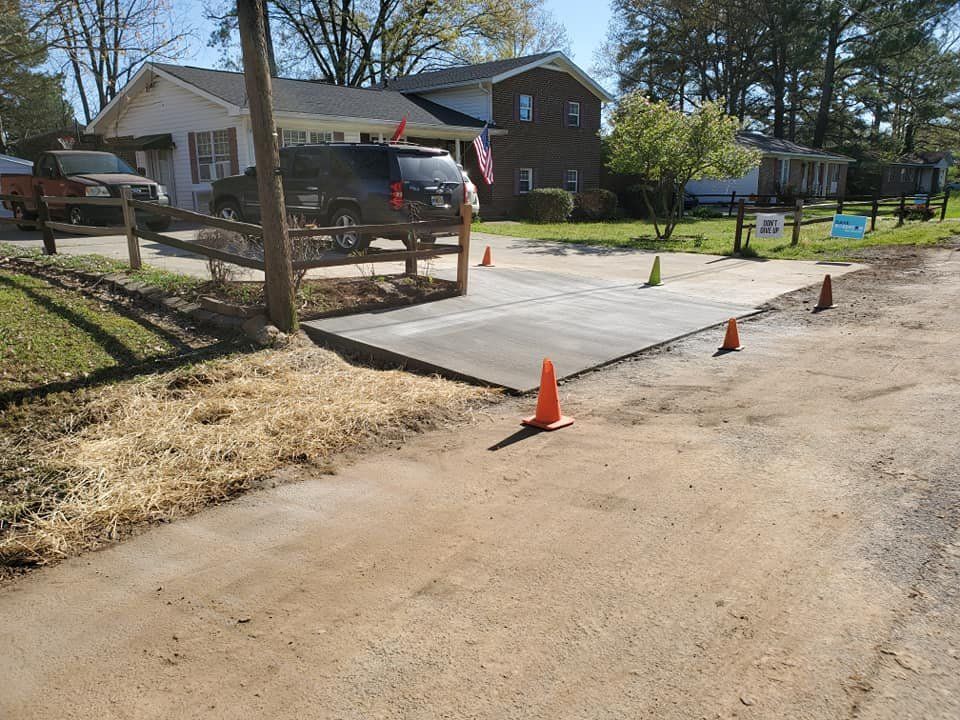 Fresh concrete driveway under construction with orange cones in a residential neighborhood