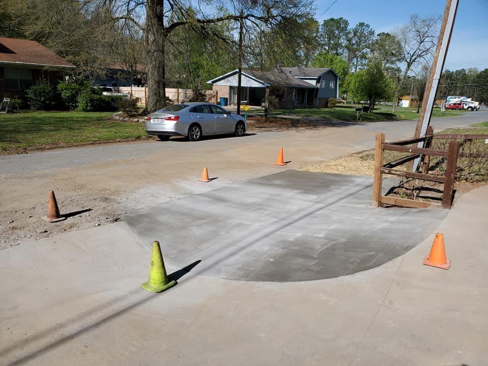 Driveway access ramp with orange cones and a parked silver car on a suburban street.