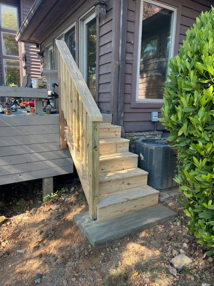 Short wooden staircase with railing leading to a raised deck beside a house