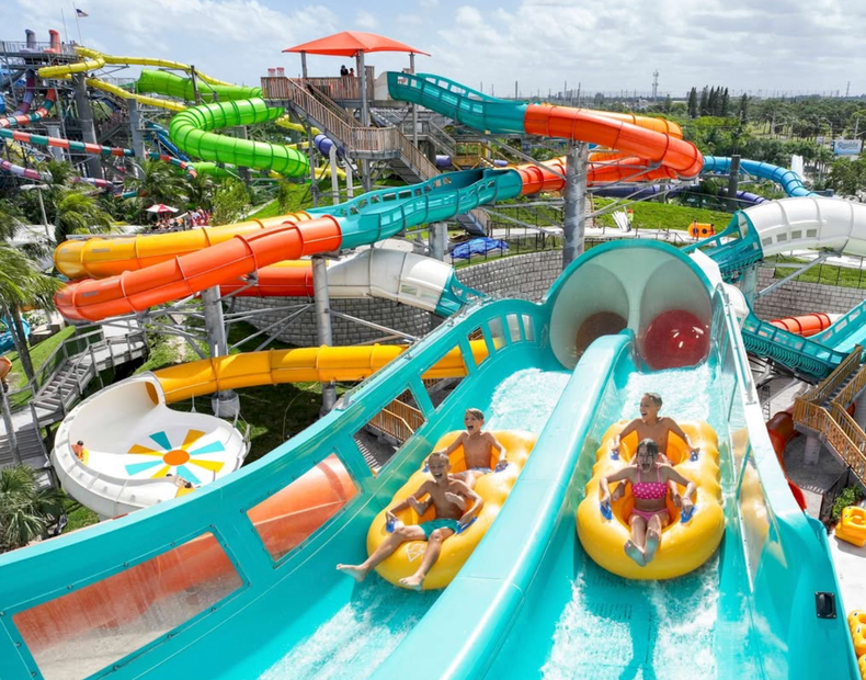 Water park with colorful twisting slides and people riding yellow tubes down a turquoise slide