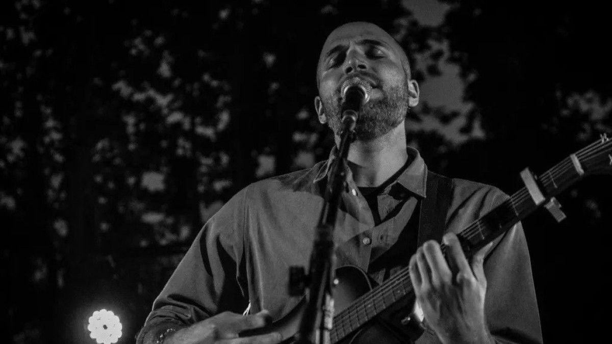 black and white image of jeremy levif singing and playing guitar