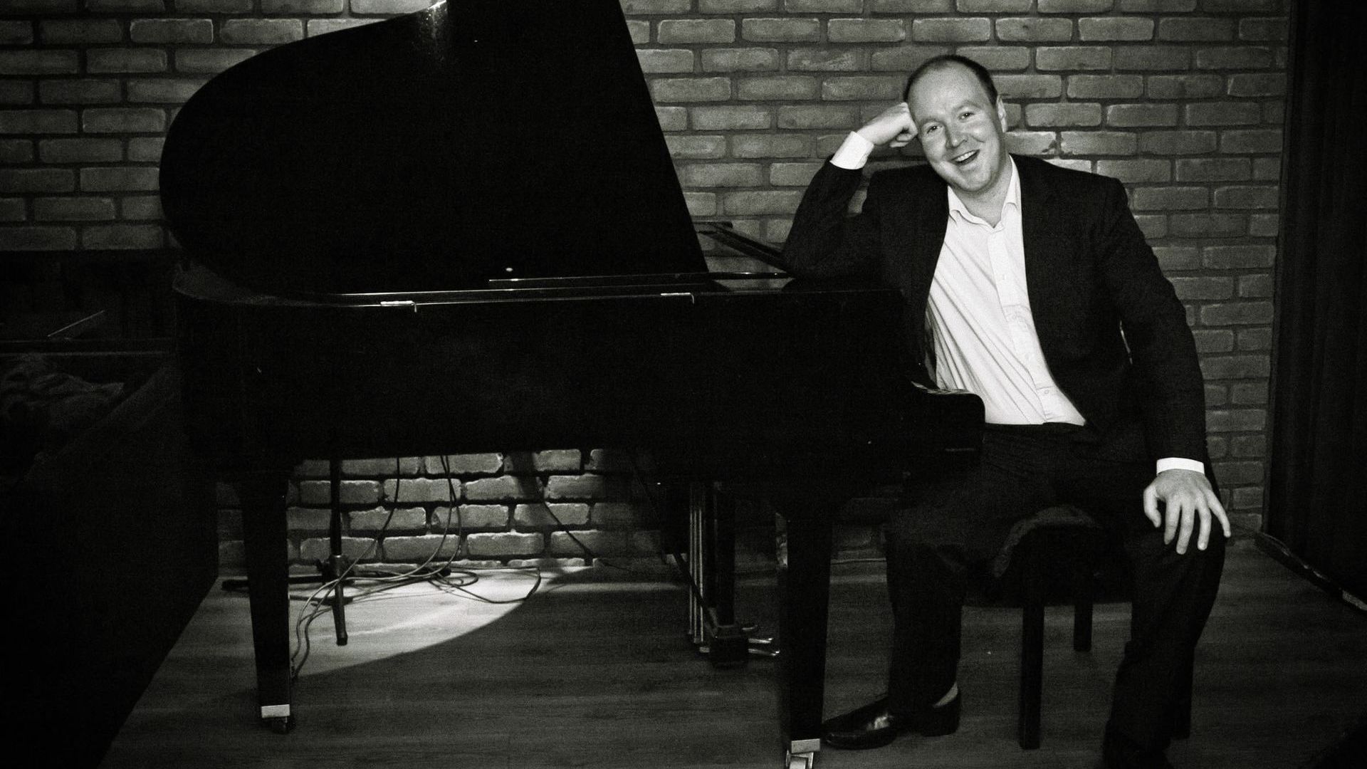 John Rankin sitting at his piano in a black and white image