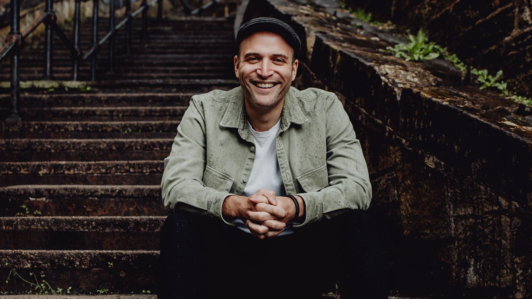 Jeremy Levif sitting on outdoor stairs, smiling at camera 