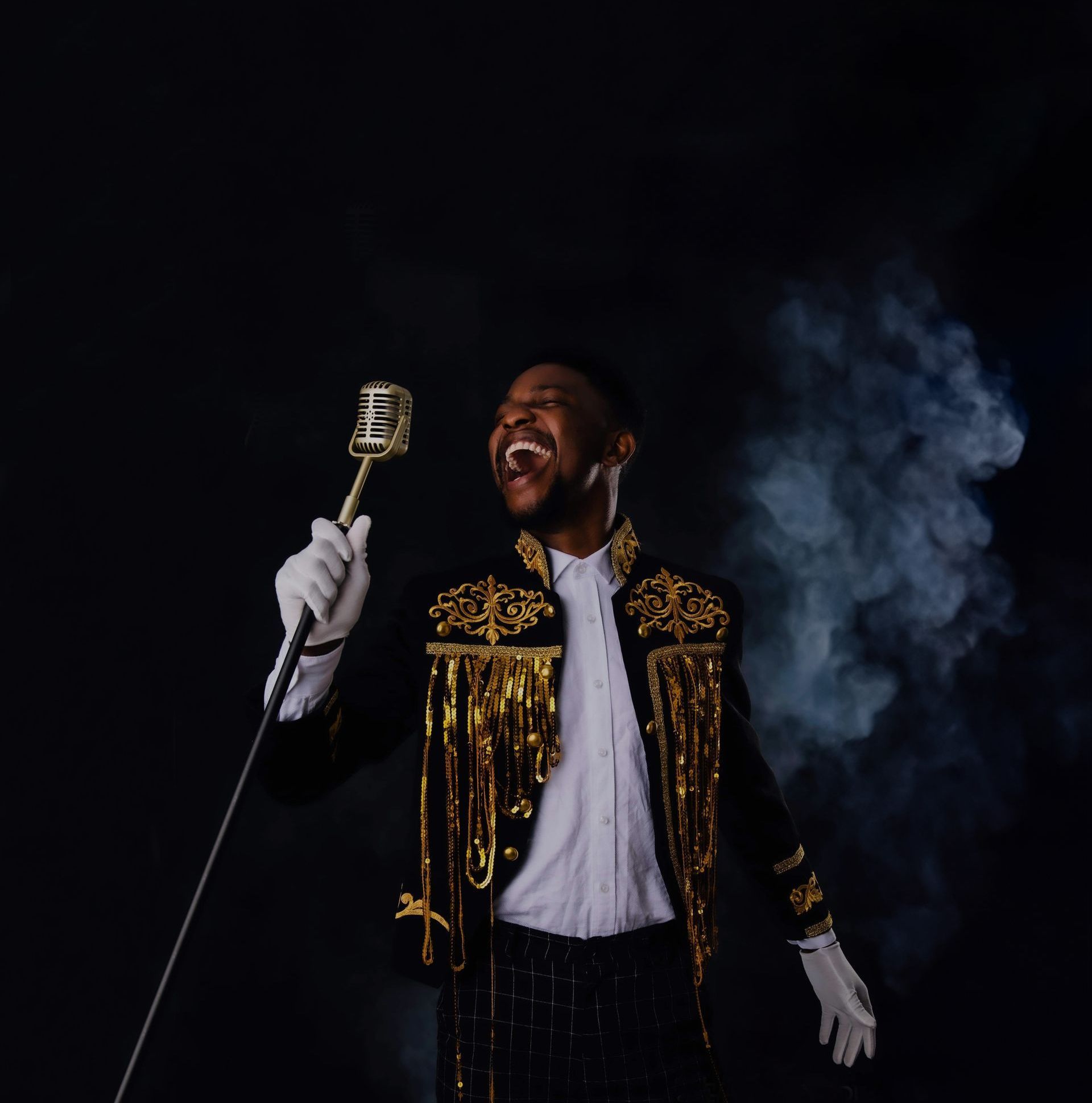 Photo of Simon Sims singing into a microphone wearing a gold and black jacket