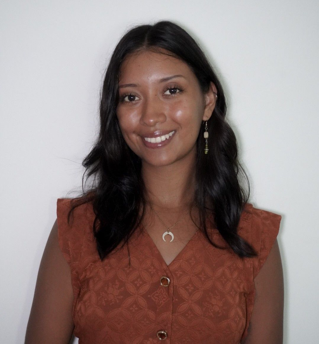 Smiling woman in a rust-colored top against a plain light background