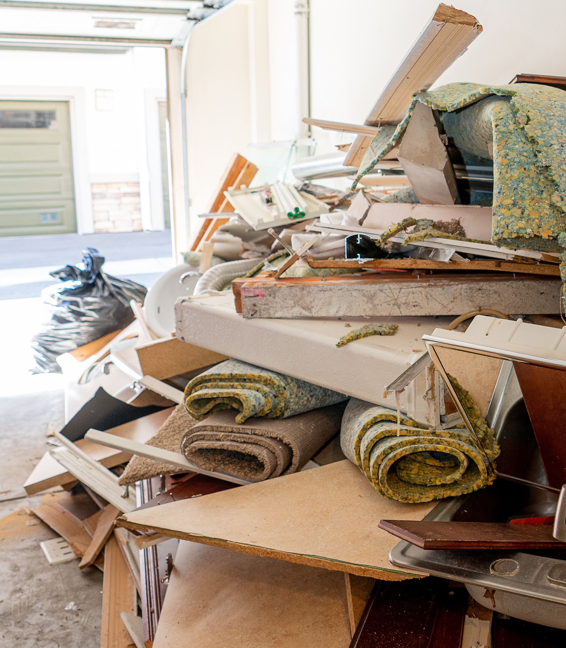 A pile of junk is sitting in a garage next to a garage door.
