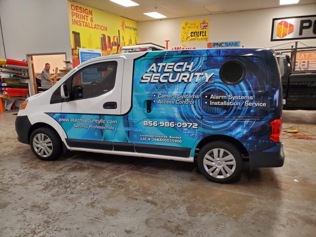 Atech Security blue-and-white service van parked indoors in a workshop.