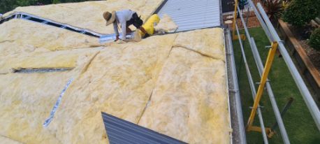 Roofer Working on a Roof Covered in Insulation, Near Scaffolding, in Daylight — Rumara Roofing in Sunshine Coast, QLD