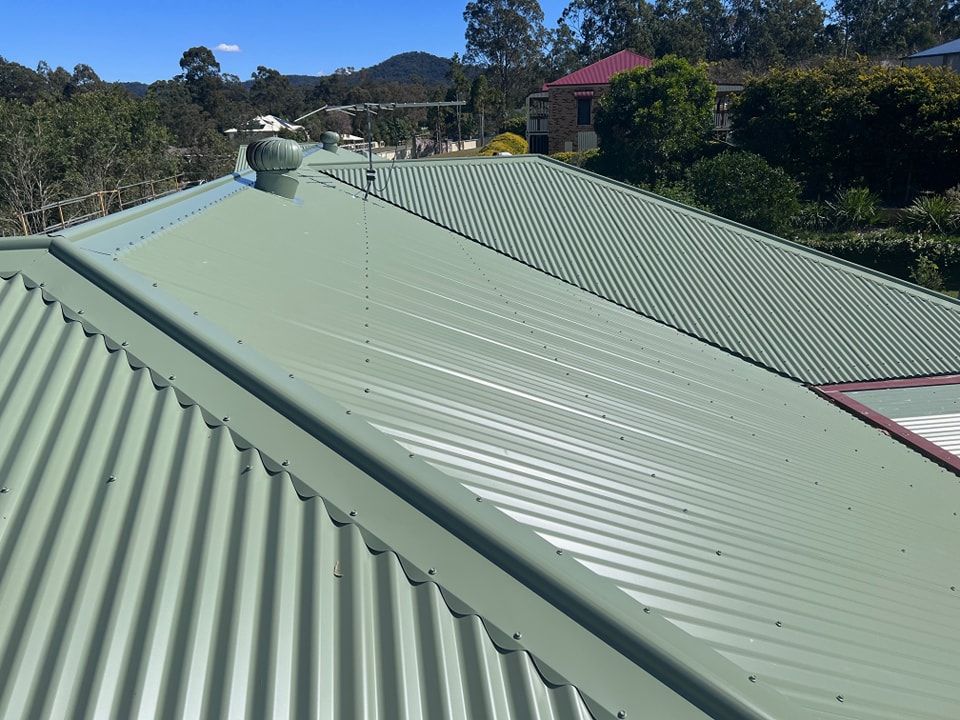 Green Corrugated Metal Roof on a House, With Trees and Hills in the Background — Rumara Roofing in Caboolture, QLD