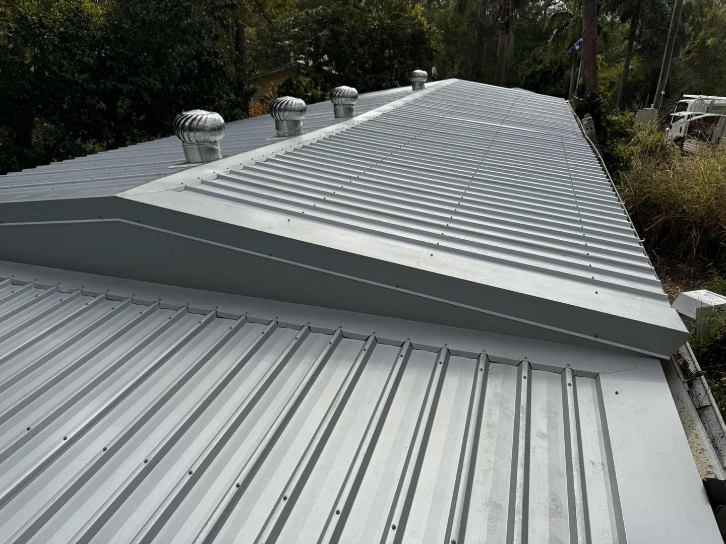 a Metal Roof With Ridges, a Few Vents, and a Sloped Section — Rumara Roofing in Sunshine Coast, QLD